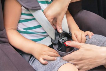 a mother buckling a child's car seat