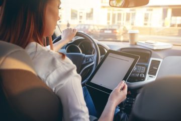 Woman distracted and driving holding a tablet