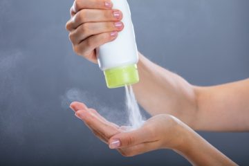 Woman pouring talcum powder in her hands.