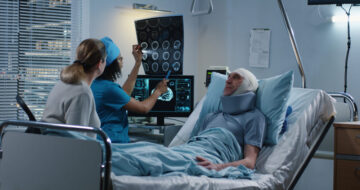 Brain injury patient in bed with his doctor and wife on the side.