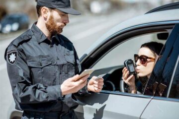 Lady driver taking the breathalyzer test if she's drunk.